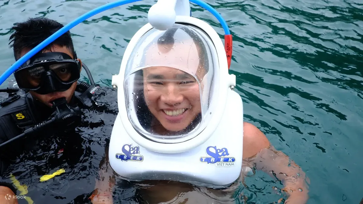 Guests walking underwater with helmets surrounded by fish